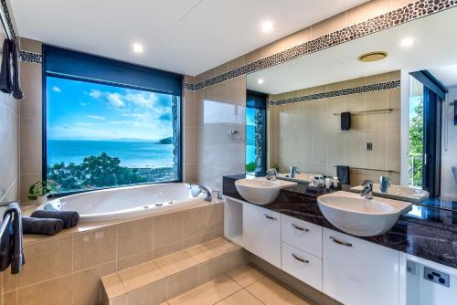 Un baño con dos lavabos y una gran ventana. en Edge 5 Oceanfront 3-Bedroom Apartment - Featuring an Infinity Pool, Spa Bath, Buggy and Valet Service, en Hamilton Island
