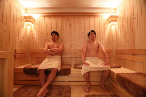 two men are sitting in a sauna at Smart Stay SHIZUKU Shinagawa-Oimachi in Tokyo