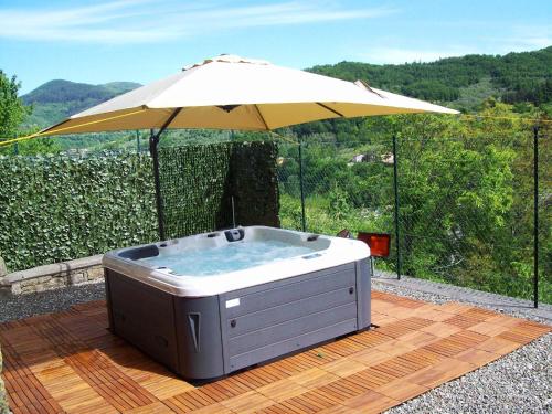 a hot tub with an umbrella on a wooden deck at Relaxing Tuscan Home with WiFi in Casola in Lunigiana