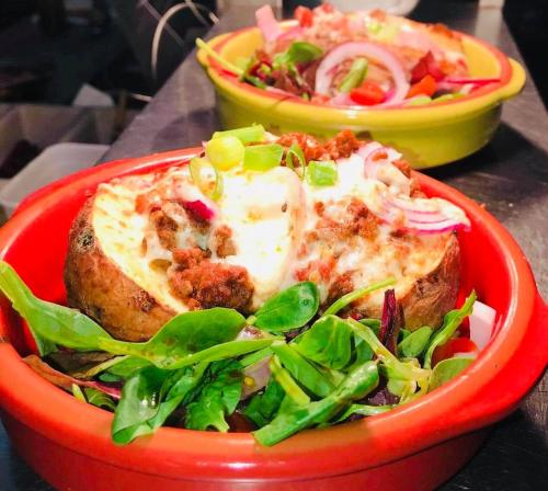 a red bowl of food with a salad and pizza at Malin TownHouse in Malin