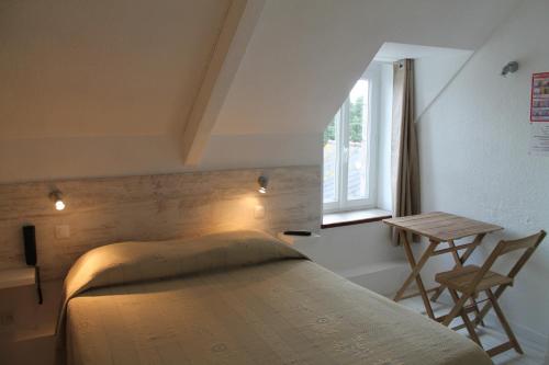 a bedroom with a bed and a table and a window at Auberge l'Air de Vent in Frehel
