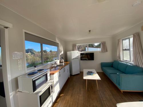 cocina y sala de estar con sofá azul en Whanganui River Top 10 Holiday Park, en Whanganui