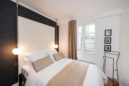 une chambre avec un grand lit blanc et une fenêtre dans l'établissement Odéon - Notre Dame Paris Climatisé-Wifi, à Paris