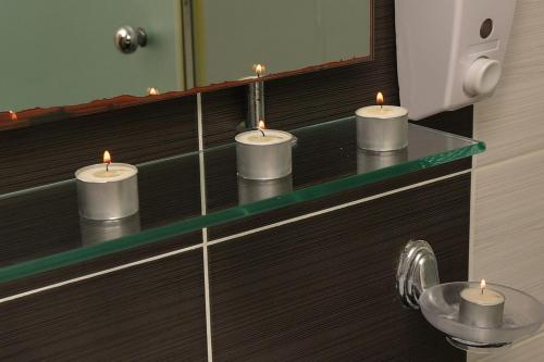 卡拉馬塔的住宿－Lida Apartments，浴室的玻璃柜台上摆放着三把蜡烛