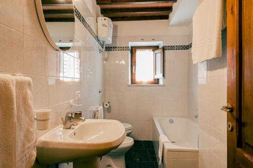 biała łazienka z umywalką i toaletą w obiekcie Il Leccio w mieście San Gimignano
