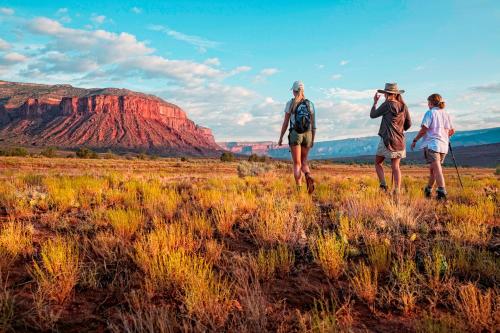 three people walking in a field with a mountain in the background at Gateway Canyons Resort, a Noble House Resort in Gateway