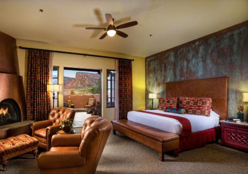 a bedroom with a bed and two chairs and a fireplace at Gateway Canyons Resort, a Noble House Resort in Gateway