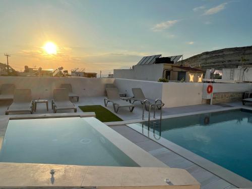 a swimming pool on the roof of a building with the sunset at Antonios Hotel Apartments in Matala