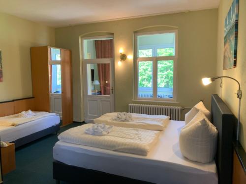 a hotel room with two beds and two windows at Pension zur Ostsee in Kölpinsee