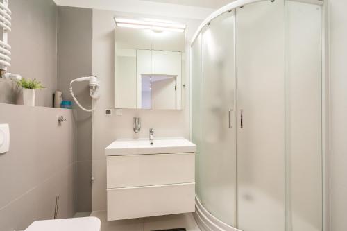 a white bathroom with a sink and a shower at Blizej Morza - Apartamenty KOMFORT fitness, ping-pong table, PlayStation in Kołobrzeg