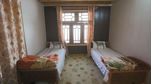 two twin beds in a room with a window at SARAI-E-HUNZA STAY & DINE in Hunza Valley