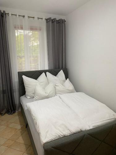 a bed with white sheets and pillows in a bedroom at Apartament Makadi in Międzyzdroje