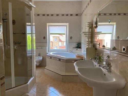 y baño con lavabo, ducha y bañera. en Apartments & Ferienhaus Senftner, en Thale