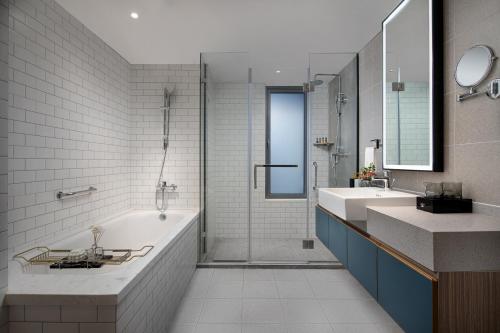 ein Badezimmer mit zwei Waschbecken, einer Badewanne und einer Dusche in der Unterkunft Citadines Yunlong Lake Xuzhou in Xuzhou
