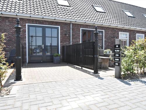 a brick house with a black gate and a door at Apartment near Groote Keeten Beach in Callantsoog