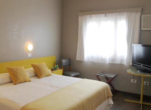 a bedroom with a large bed and a television at Hotel Posada Del Sol in Salta