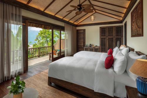 a bedroom with a white bed and a balcony at Avana Retreat in Mai Chau