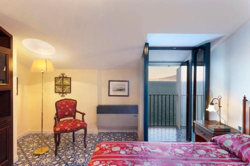 a bedroom with a bed and a chair and a window at Hotel La Tonnarella in Sorrento