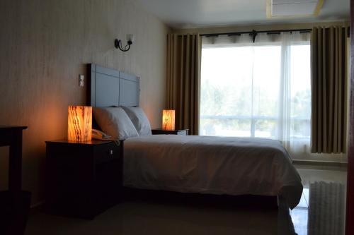 a bedroom with a bed and a large window at Hotel Casablanca Xicotepec in Xicotepec de Juárez