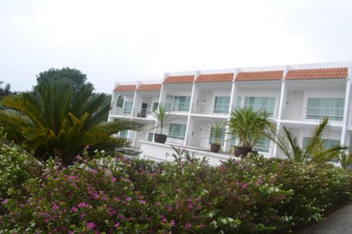 a white building with palm trees and plants at Hotel Casablanca Xicotepec in Xicotepec de Juárez