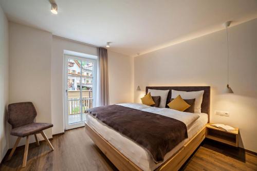 um quarto com uma cama, uma cadeira e uma janela em Engel Appartements Stodl em Parcines