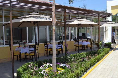 a restaurant with tables and chairs under umbrellas at Hotel Casablanca Xicotepec in Xicotepec de Juárez