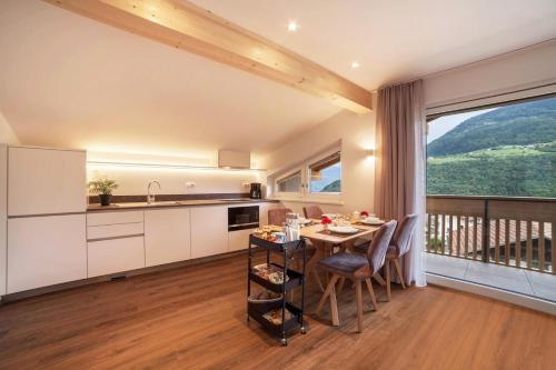 a kitchen and dining room with a table and a balcony at Engel Appartements Summerfrisch in Parcines