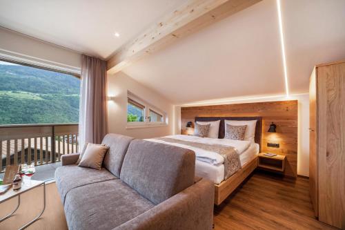 um quarto com uma cama e um sofá em Engel Appartements Summerfrisch em Parcines