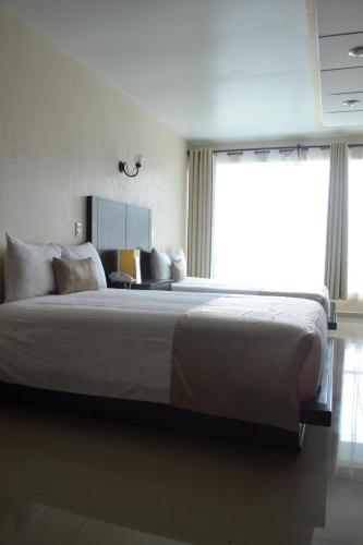 a bedroom with a large bed with a large window at Hotel Casablanca Xicotepec in Xicotepec de Juárez