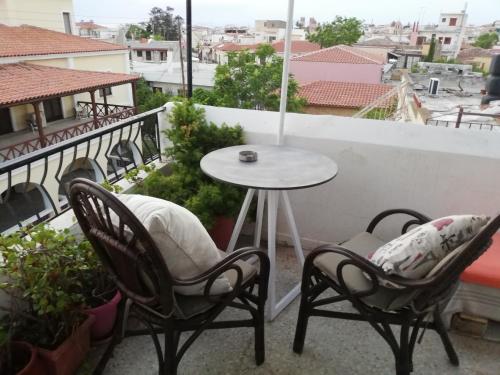 a patio with two chairs and a table on a balcony at Captain's Rooms in Aegina Town