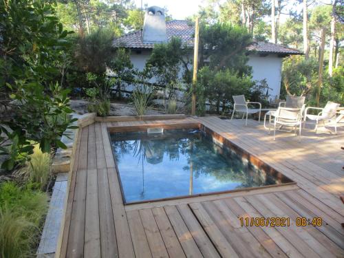 - une piscine sur une terrasse en bois avec une table et des chaises dans l'établissement une maison lumineuse sous les pins, à Le Canon