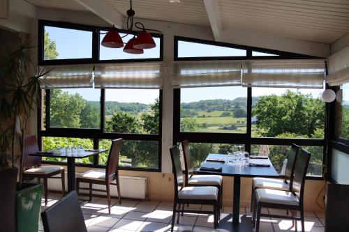 een eetkamer met ramen, tafels en stoelen bij Auberge des 7 Tours in Martel