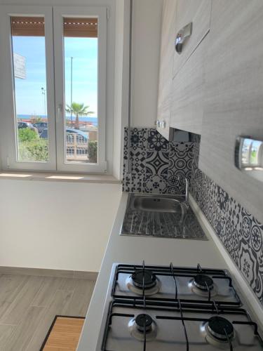 een keuken met een fornuis top oven naast een raam bij Appartamento fronte mare con giardino in Porto Recanati