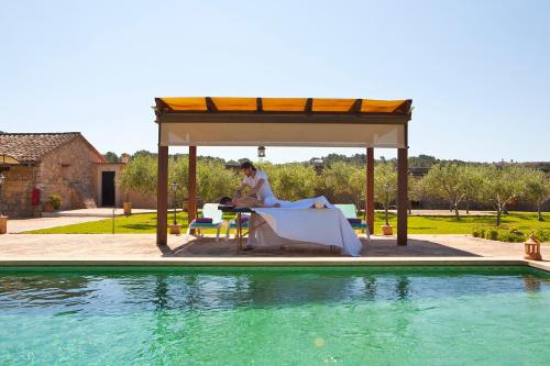 a woman sitting in a gazebo next to a pool at S'Hort de Son Caulelles - Adults Only in Marratxí 