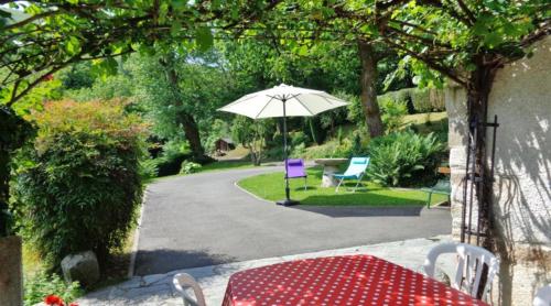 - une table et des chaises avec un parasol dans le jardin dans l'établissement Le gîte d'en haut, à Jarret