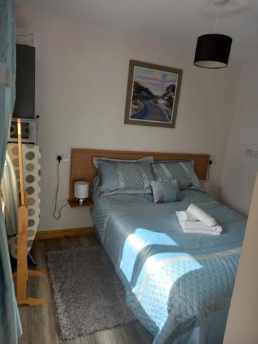 a bedroom with a bed with a blue comforter at Country Cottage Apartment Valentia Island Kerry in Valentia Island