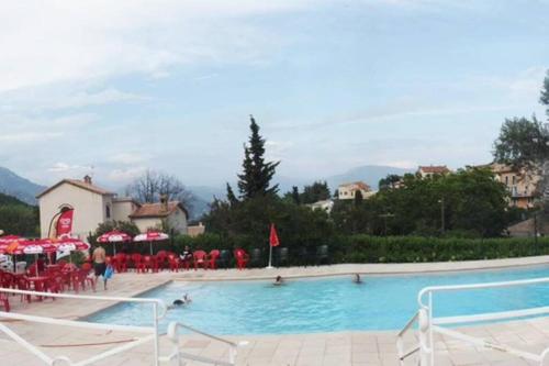 a large swimming pool with red chairs and umbrellas at Joli studio entre mer et montagne proche de Nice in Bouyon