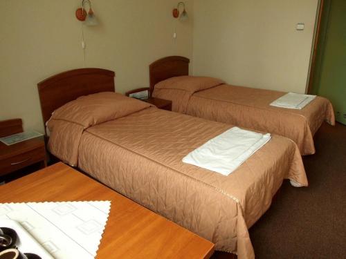 クラクフにあるPastoral Lodge at the Sanctuary of the Divine Mercyのベッド2台とテーブルが備わるホテルルームです。