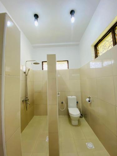 a bathroom with a toilet and a glass shower at Habibis Bottle House in Nungwi