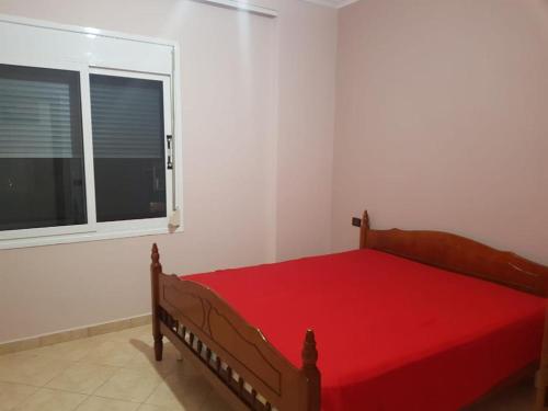ein Schlafzimmer mit einem roten Bett und einem Fenster in der Unterkunft LUXURY SEASIDE APARTMENT WITH TWO BEDROOMS 130 meter in Vlorë