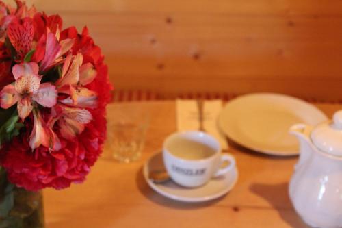 a table with a cup of coffee and a vase with flowers at Hotel Askania 1927 in Bad Wiessee
