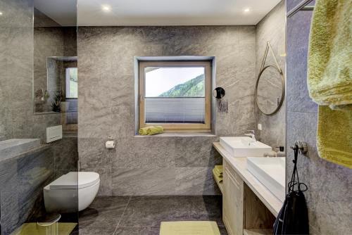 a bathroom with a toilet and a sink and a window at Ju and Me Garden Lodge in Rauris