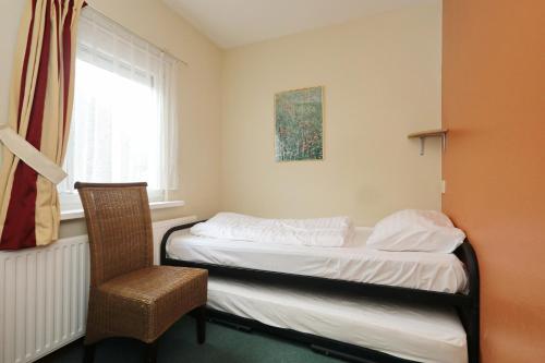 1 dormitorio con 1 cama, 1 silla y 1 ventana en De Zeemeeuw en Noordwijkerhout