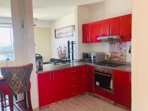 a red kitchen with red cabinets and a stove at Afsaal Beach Heaven in Amanzimtoti