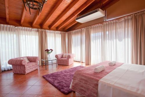 a bedroom with a bed and two chairs and windows at S'Hort de Son Caulelles - Adults Only in Marratxí 