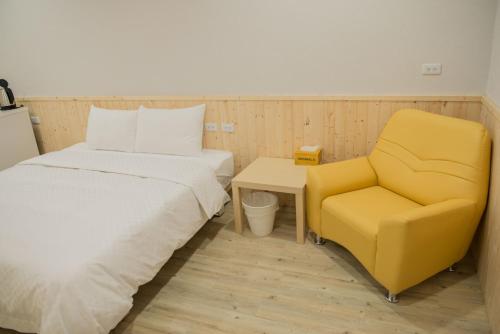 a bedroom with a bed and a yellow chair at Didi House in Tainan