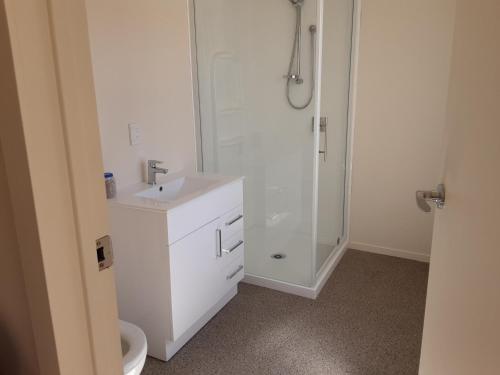 a white bathroom with a shower and a sink at I'm a traveller in Dunedin