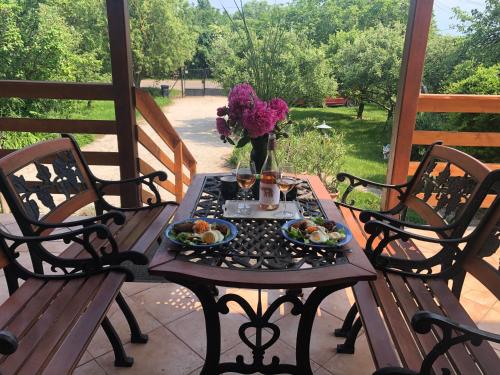 una mesa con platos de comida y flores en un porche en Balaton Vendégház Paloznak, en Paloznak