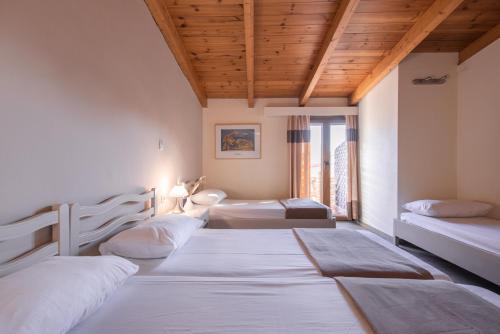 a room with three beds and a wooden ceiling at Yria Hotel in Zakynthos Town