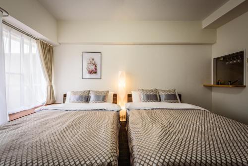 two beds in a room with a window at Cocostay The Peace Memorial Park ココステイ平和記念公園 Excellent location overlooking Peace Park! in Hiroshima